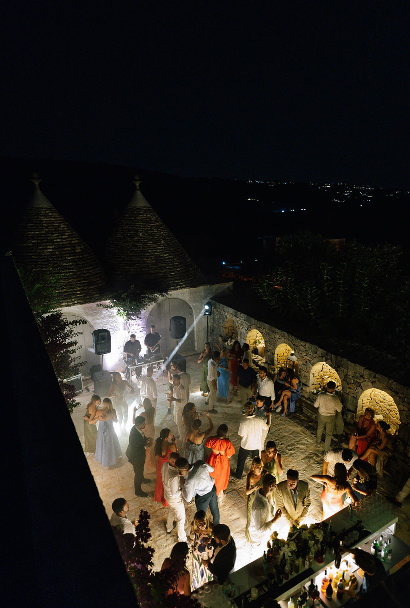 Wedding guests dancing beneath the trulli at night, seen from above
